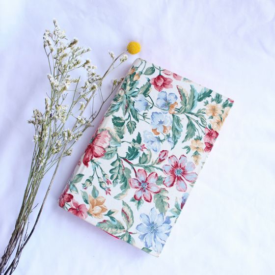 Floral-patterned notebook beside dried blooms — photo by vics ilustrada on Pexels