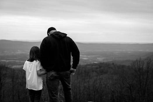 Black and white photo of a father and daughter bonding in a scenic outdoor setting.