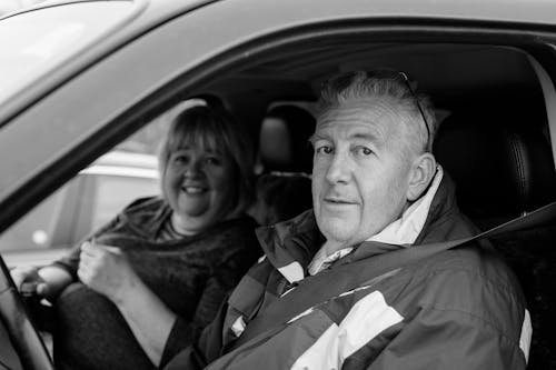 Grayscale Photo of Man and Woman Inside the Car