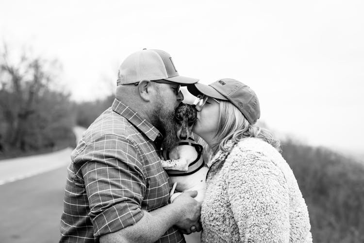 A Couple Kissing Their Dog 