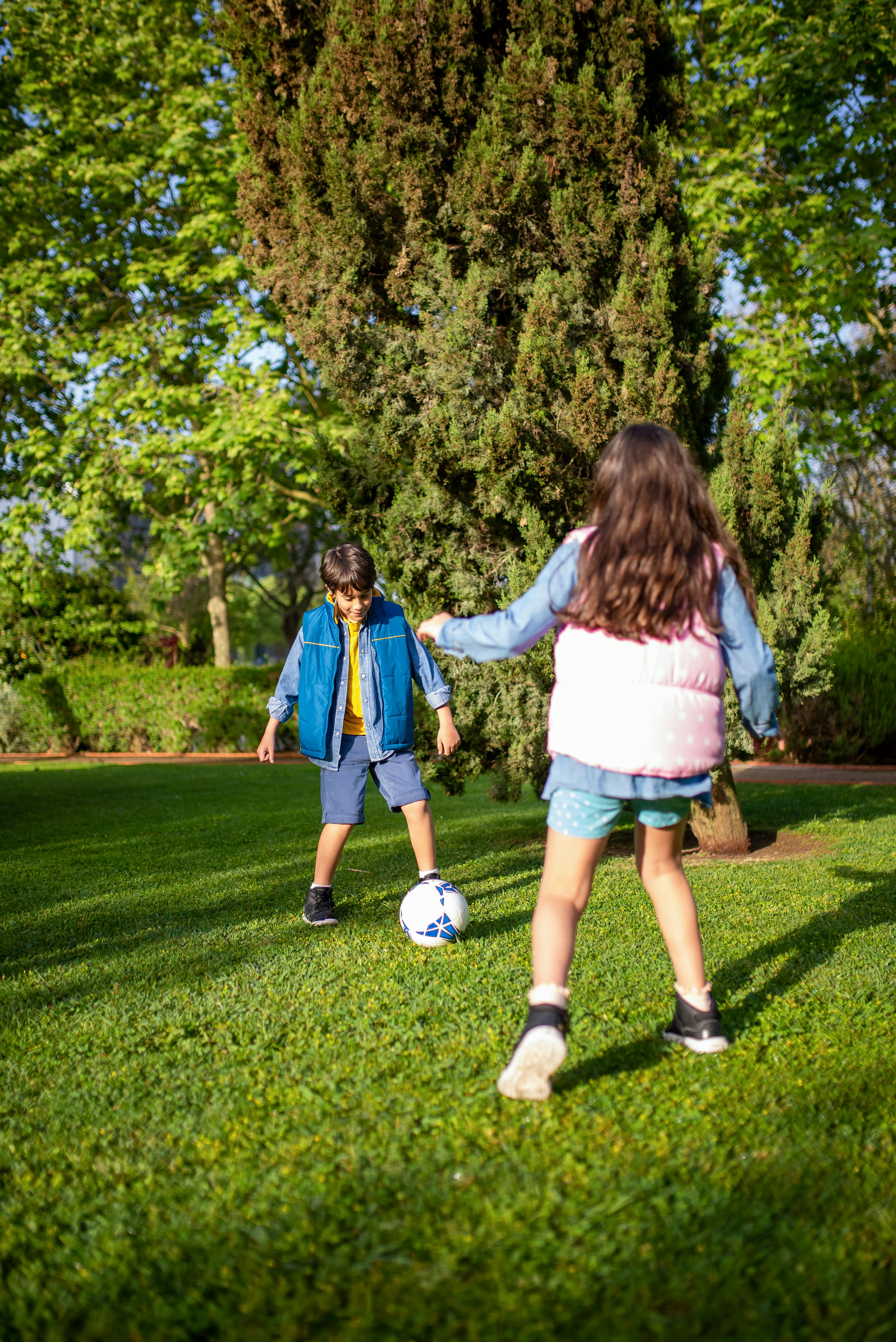 two children playing football on green grass