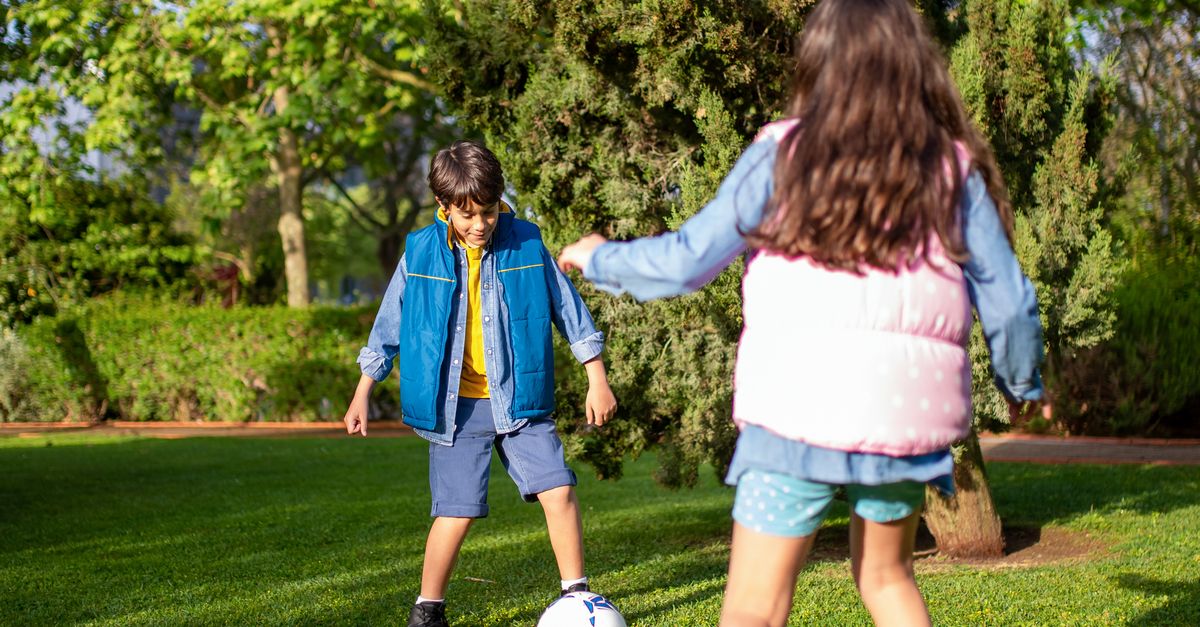 Rüyada Kardeşle Futbol Oynamak - Rüya Tabiri ve Anlamı - Kids enjoy a fun game of soccer on a bright and sunny day in a lush green park.