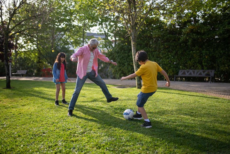 
A Man Playing Soccer With His Grandchildren