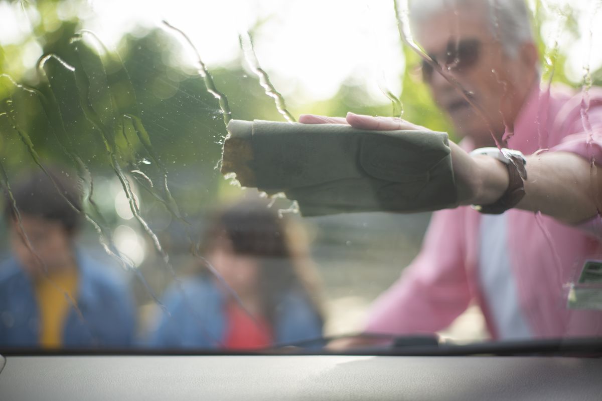 Pessoa secando o para-brisa de um carro