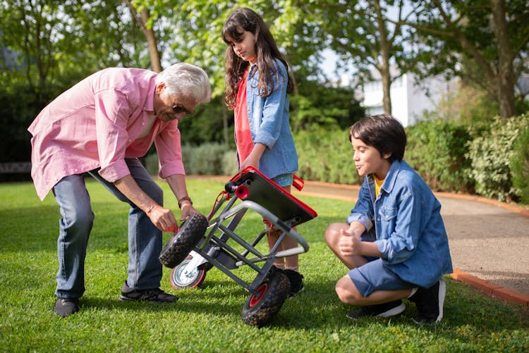 Man In Pink Top Fixing A Garden Cart