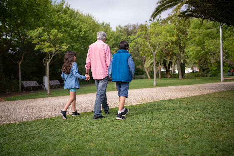 Elderly Man Walking At The Park With Grandchildren