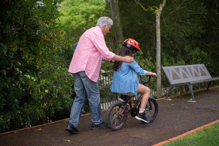 An Elderly Man Teaching His Grandchild To Ride A Bike