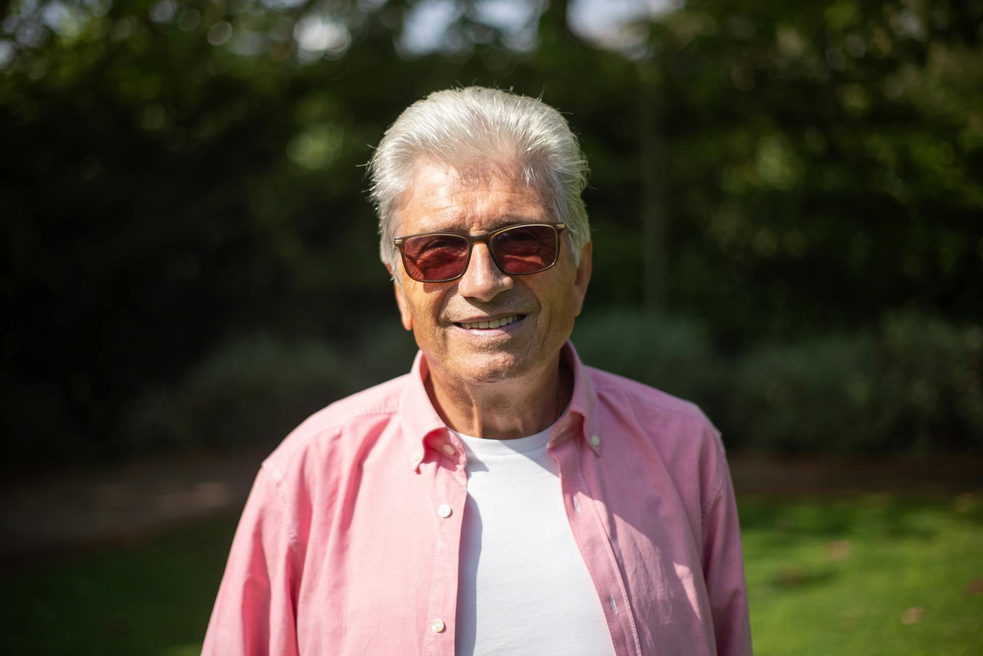 Portrait of a relaxed senior man in sunglasses smiling outdoors under sunny skies in Portugal.