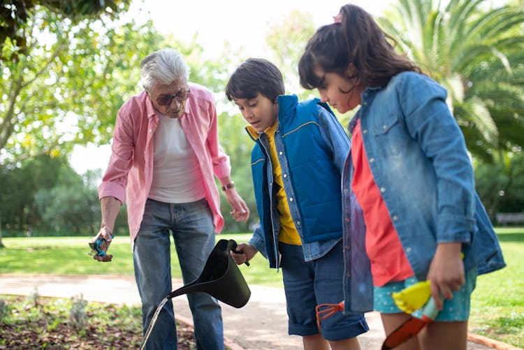 An Elderly Man Gardening With His Grandchildren