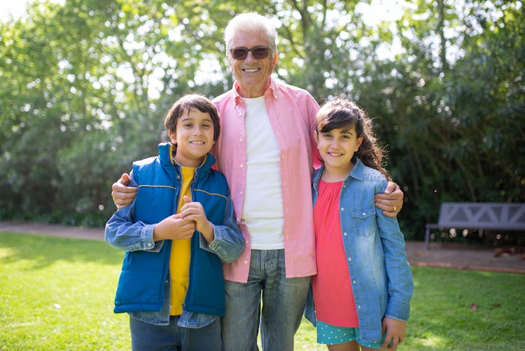 An Elderly Man With His Grandchildren At A Park