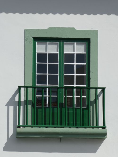 Free Elegant green-framed balcony window on a pristine white wall in direct sunlight. Stock Photo