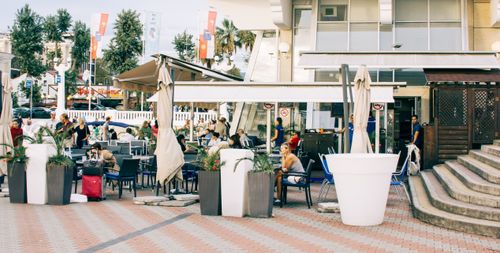 Free Busy outdoor café with modern architecture and seating under umbrellas. Stock Photo