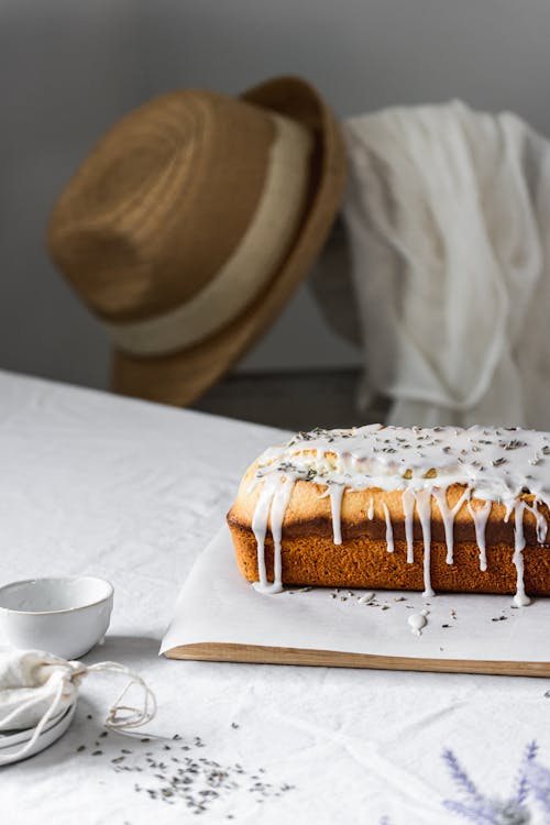 Cake with Icing Lying on the Table with a Hat on a Chair in the Background 