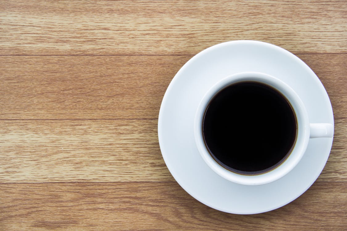Free Close-Up Shot of a Cup of Coffee on a Wooden Surface Stock Photo