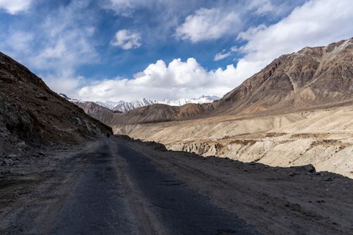 Free Remote mountain road with stunning views of rugged terrain and blue skies, capturing adventure and nature's beauty. Stock Photo