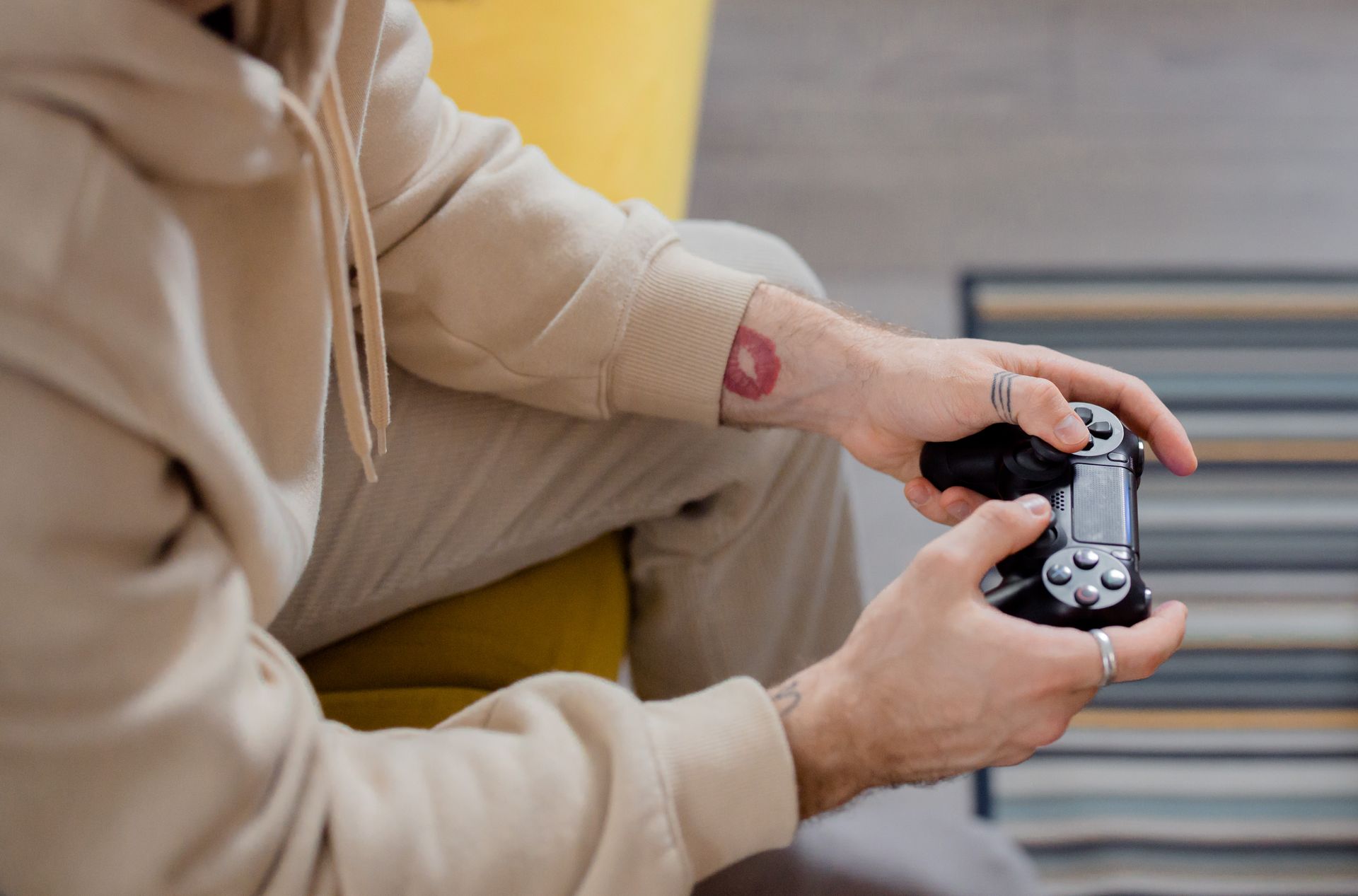 Hands holding a gaming controller with a lipstick mark, wearing long sleeves, casual setting.