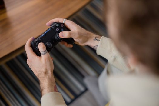 Detailed view of a person holding a gaming controller indoors, emphasizing the gameplay action.