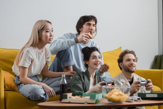 Group of friends enjoying video games and snacks on a cozy indoor sofa setting.