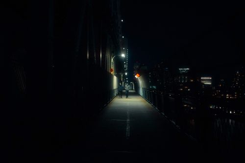 Free People walking on dark walkway with streetlight placed on bridge in modern city in night time Stock Photo