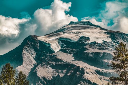 Free Stunning view of a glacier-covered mountain peak under a vibrant blue sky and fluffy clouds. Stock Photo