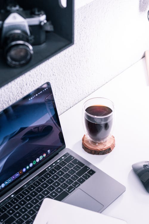Free High-Angle Shot of a Laptop beside a Glass of Beverage Stock Photo