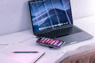 Modern laptop and smartphone near opened notepad for studies