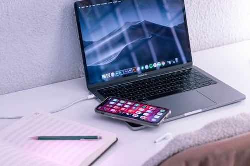 Free High angle of opened netbook with mobile phone placed near notepad and wireless earbuds for online work or studies Stock Photo