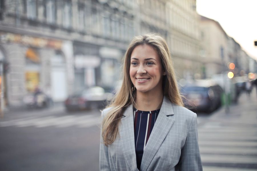 Confident woman smiling outdoors on a city street — photo by Andrea Piacquadio on Pexels