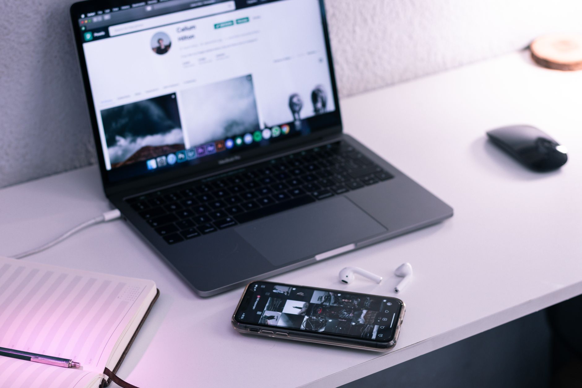 A minimalist workspace featuring a laptop, smartphone, and earbuds on a sleek desk.