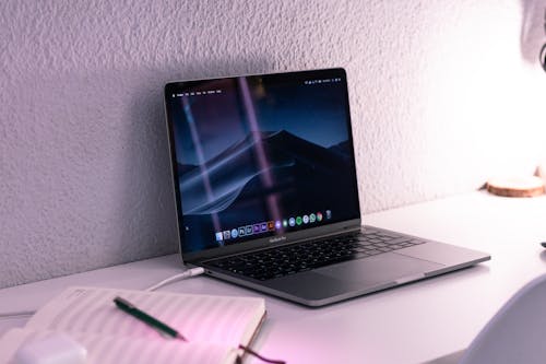 Modern laptop near pen on notepad on desk