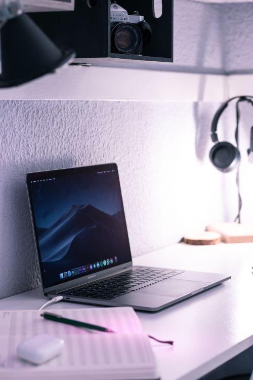 Free Modern netbook charging on table near notebook with TWS earbuds case and pen for studies Stock Photo