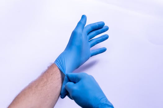 A person putting on blue medical gloves, close-up view.