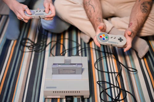 Two People holding Game Consoles 