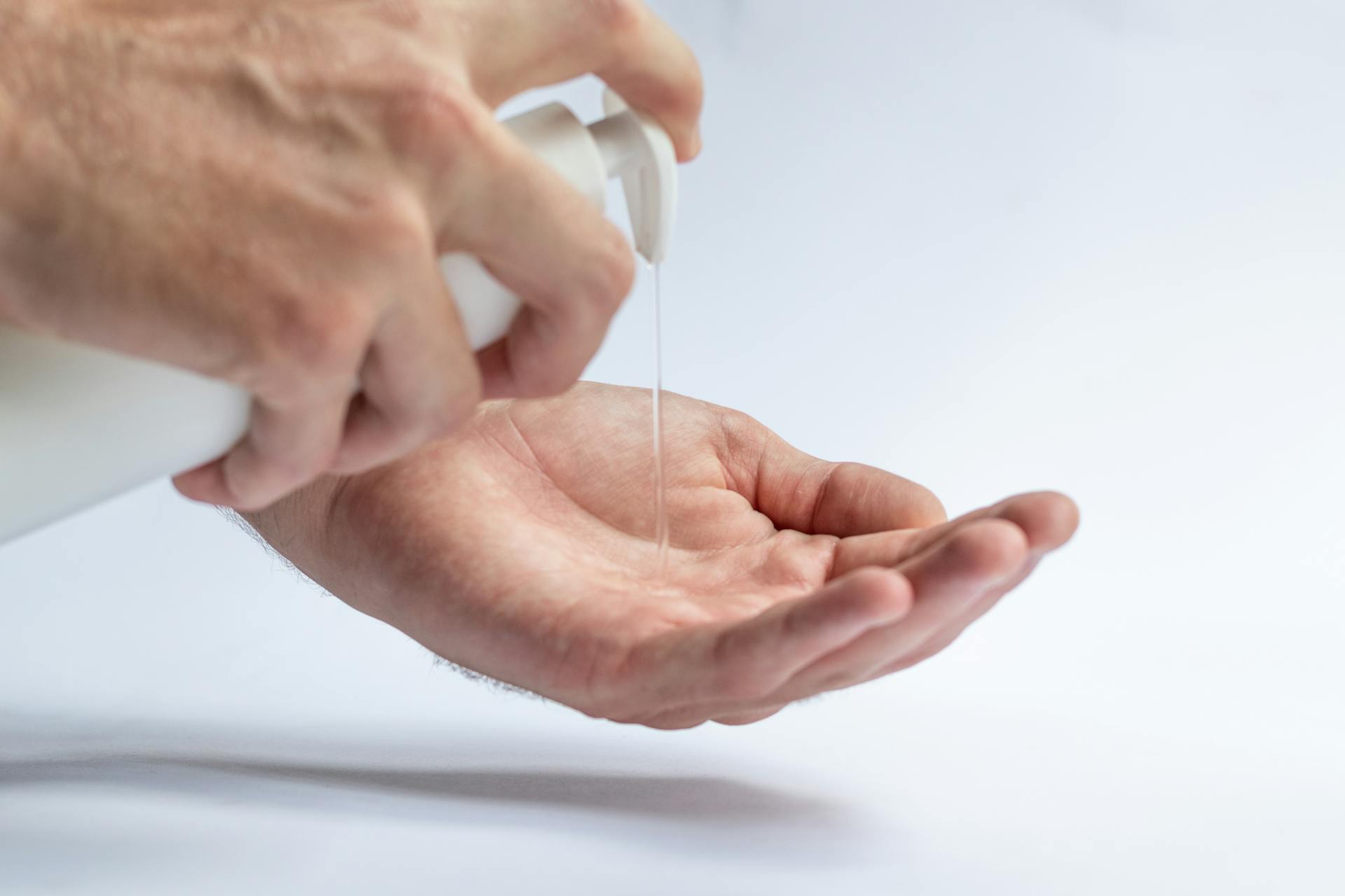 Crop anonymous male pouring antibacterial soap sanitizer for preventing spread of diseases and avoid infections