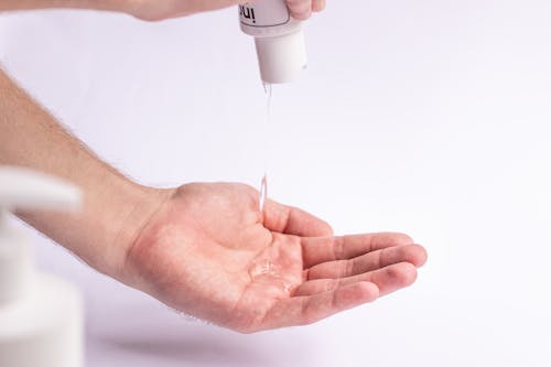 Free Crop anonymous male applying antibacterial gel on hand for daily hygiene routine and preventing spread of COVID Stock Photo