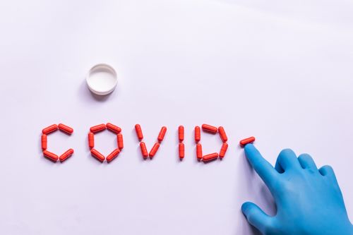 Free Top view of crop unrecognizable medical practitioner in medical glove making word COVID with capsules for treating infection Stock Photo