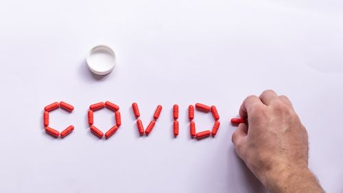 Free Top view of male making COVID composition with bright capsules for medical treatment on white background Stock Photo