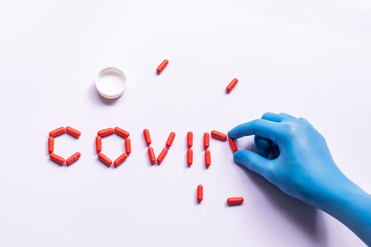 Doctor In Glove Arranging Capsules In Word COVID