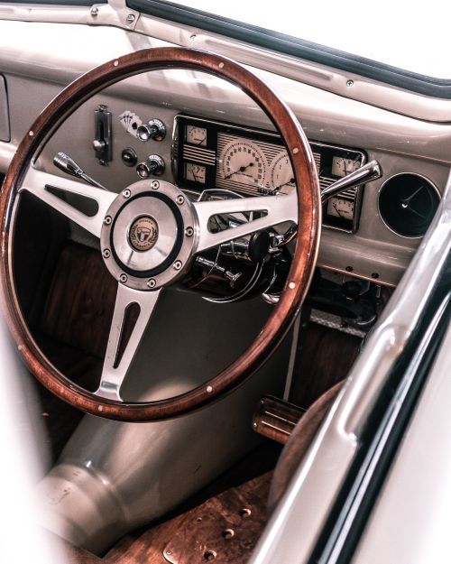 Free Close-up of vintage car dashboard featuring a wooden steering wheel and classic speedometer. Stock Photo
