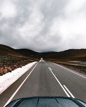 Desolate country road stretches beneath heavy clouds, creating a mood of solitude and adventure.