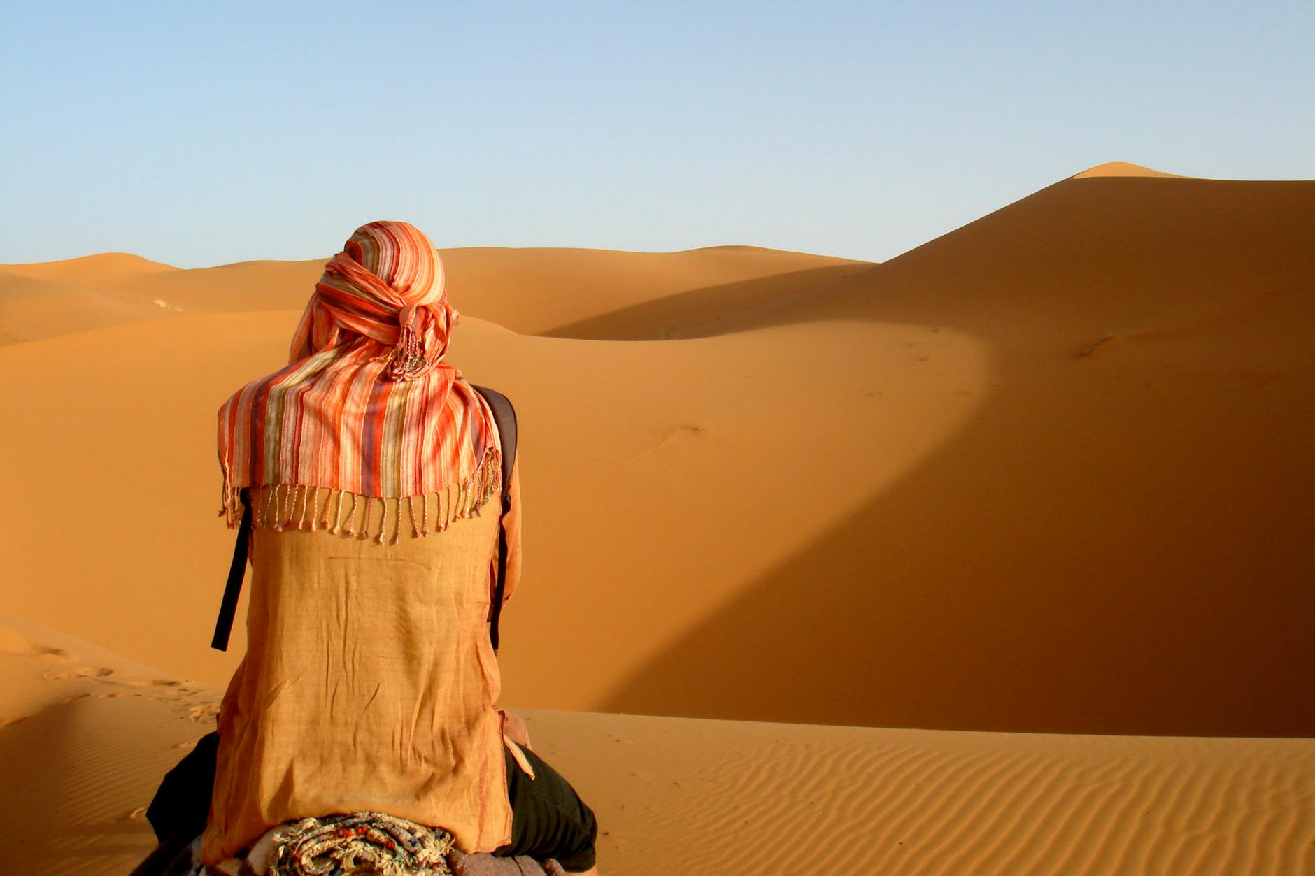 Traveler viewed from behind, admiring Morocco's striking sand dunes.