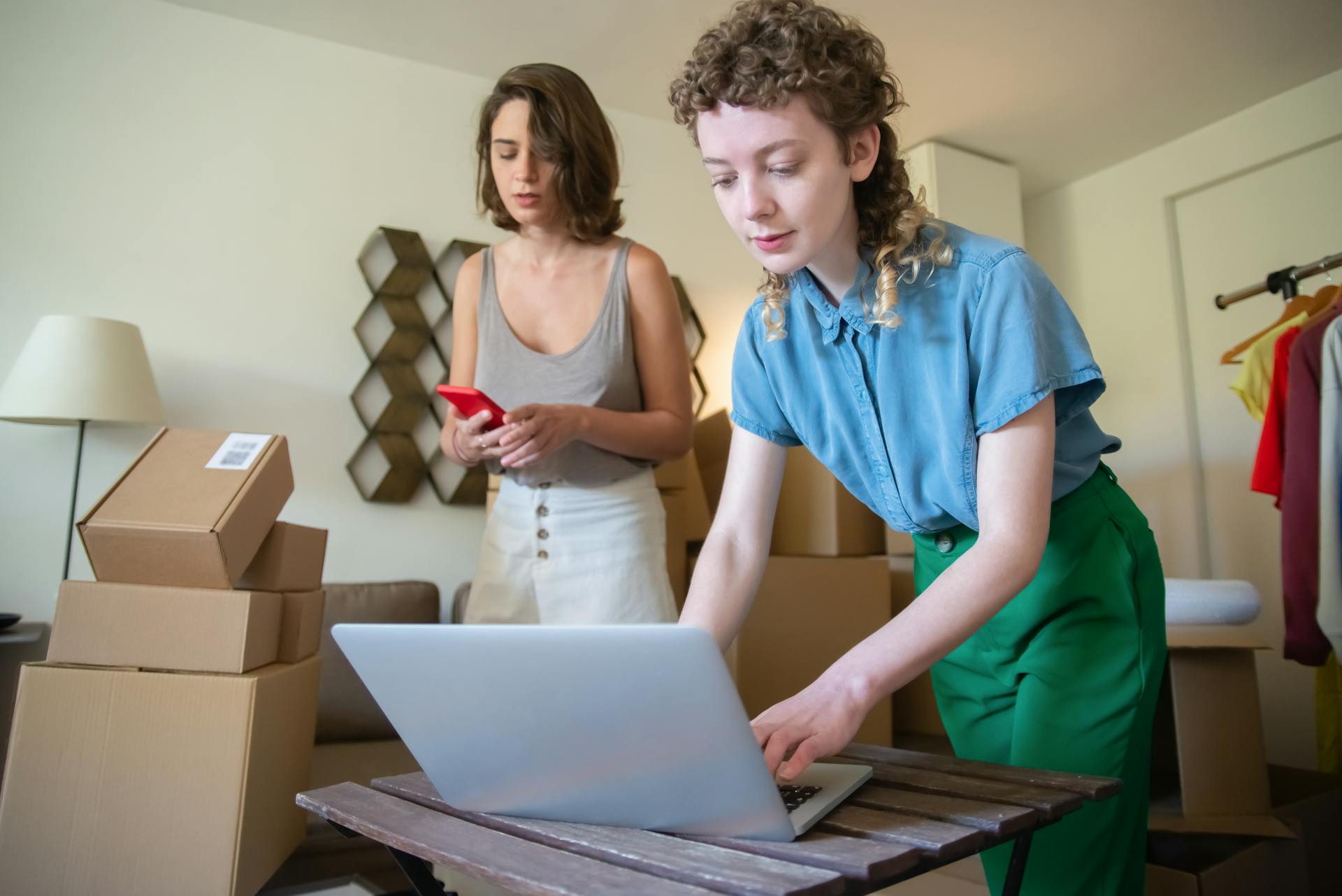 Two women organize inventory and manage orders on the laptop in an office setting.