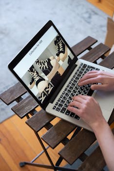 Hands browsing sneakers on laptop, showcasing online store shopping experience.