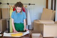 Woman in Blue Button Up Shirt Standing Beside Brown Cardboard Box
