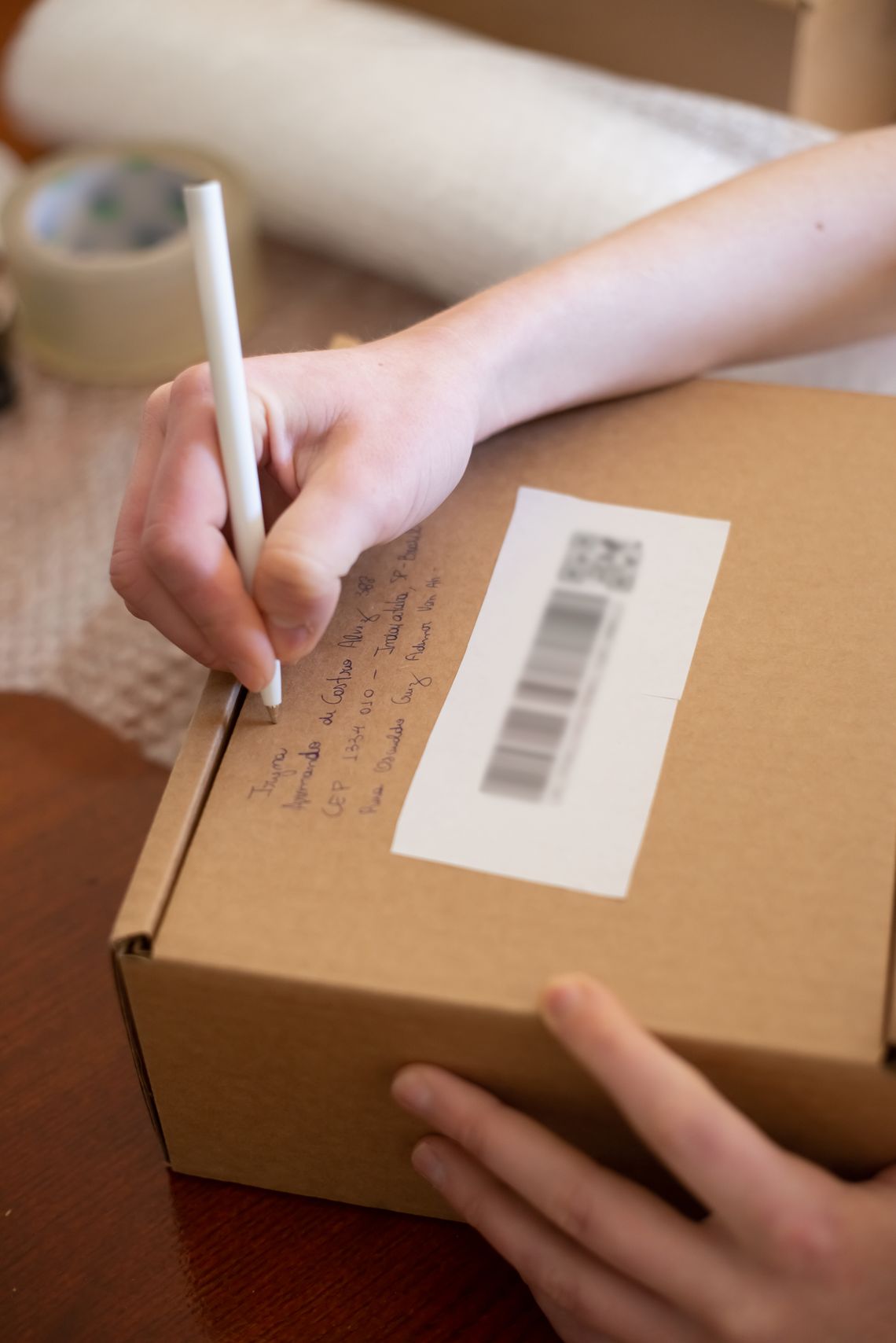 Hand writing return details on a cardboard shipping box