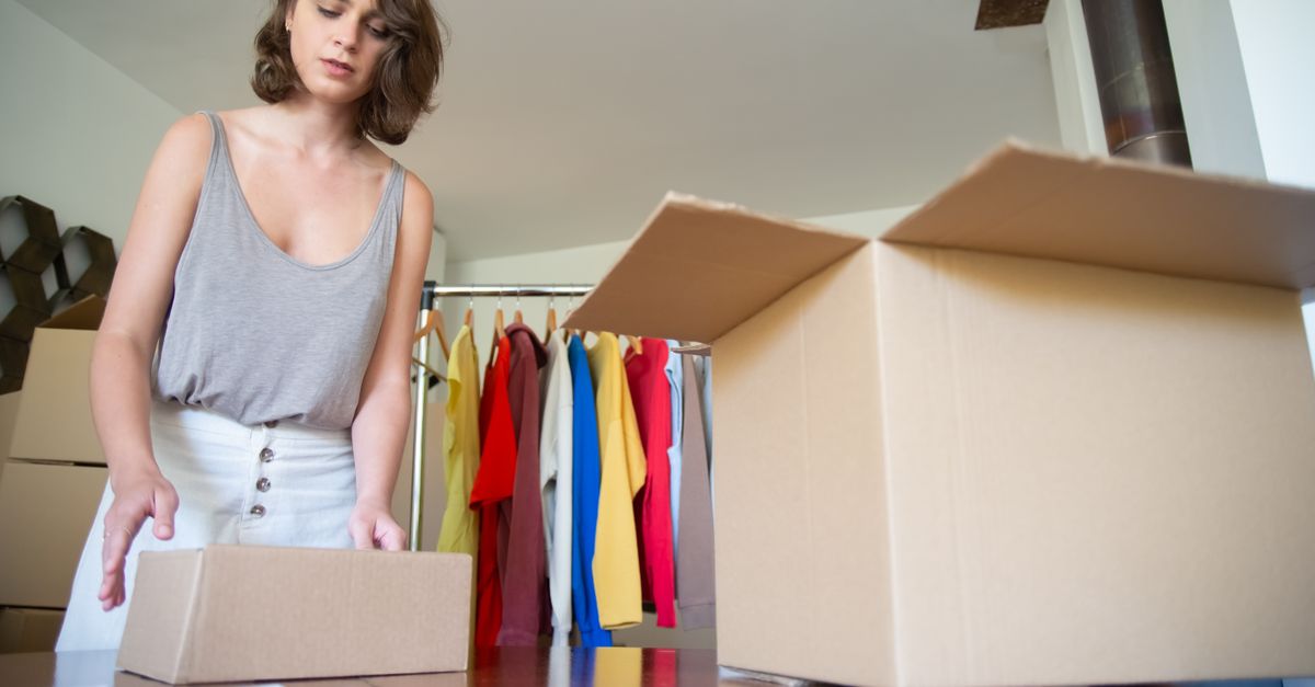 Mulher embalando caixas em um ambiente de loja de roupas, organizado para negócios e envio.