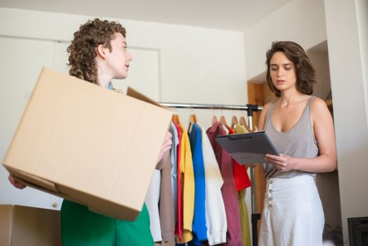 Two women organizing clothes for an online shop. Business setup indoors.