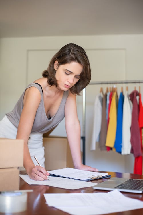 Woman in Gray Tank Top writing on Paper 