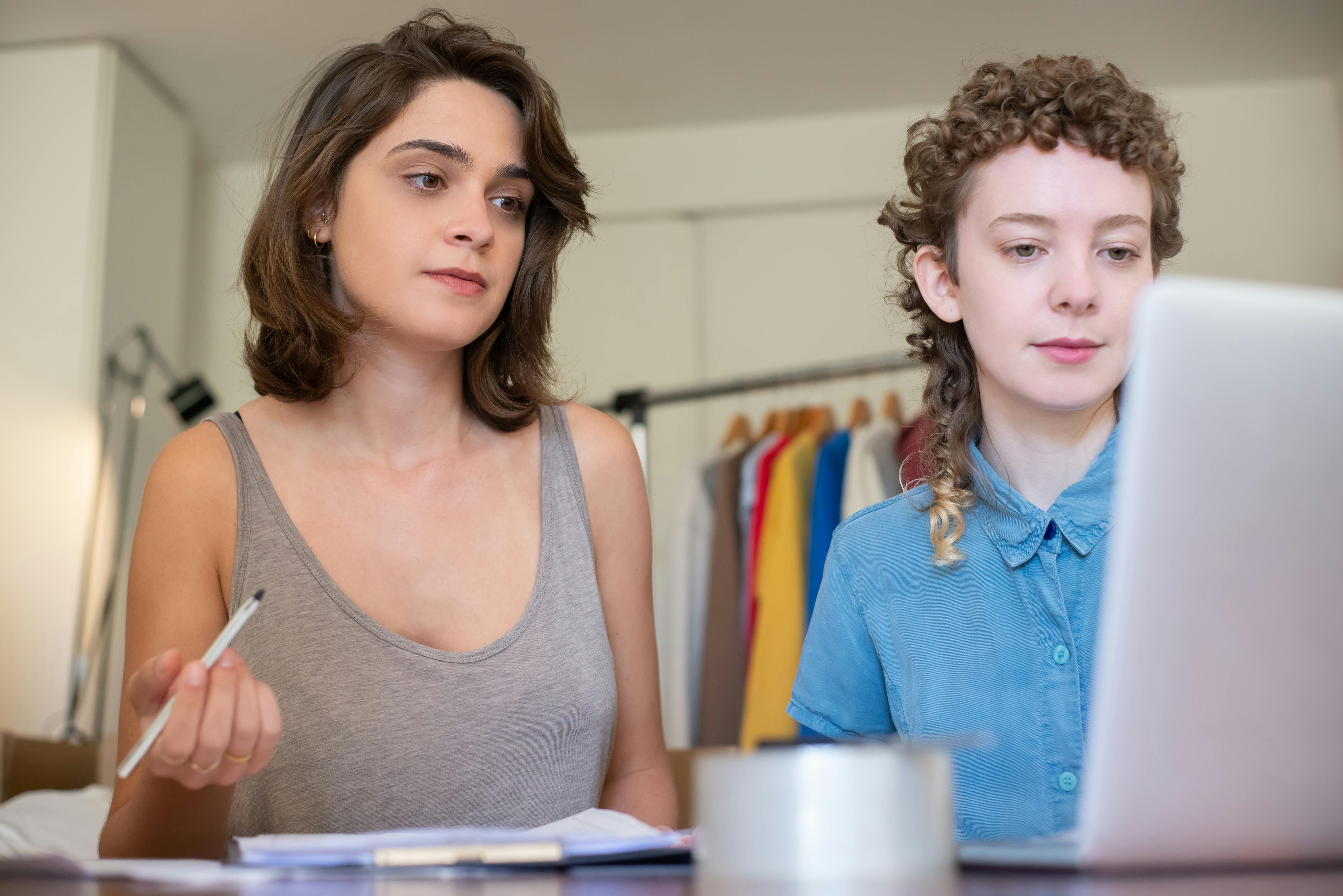 female business partners preparing parcels looking at a laptop