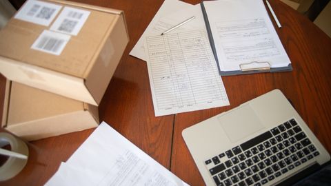Flat lay of a workspace with laptop, documents, and cardboard boxes for e-commerce operations.